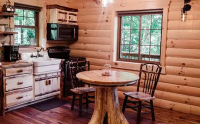 a kitchen with a table and chairs in a cabin at Cricket Hill Treehouse by Amish Country Lodging in Millersburg